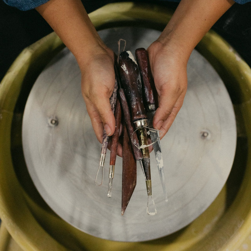 Person holding tattoo needles over a metallic surface